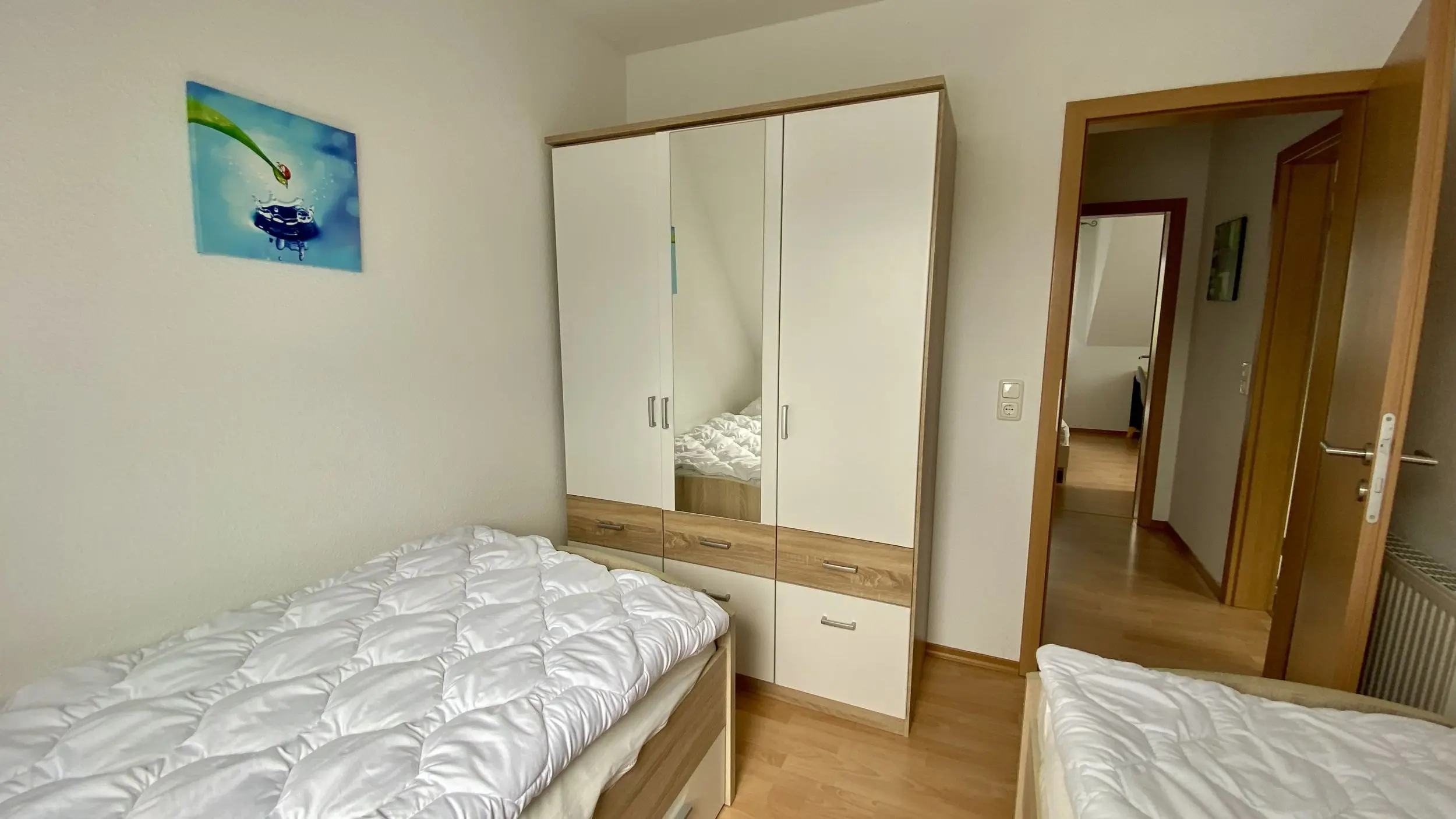 Bedroom with two single beds and a large white wardrobe with mirrored doors on the opposite wall