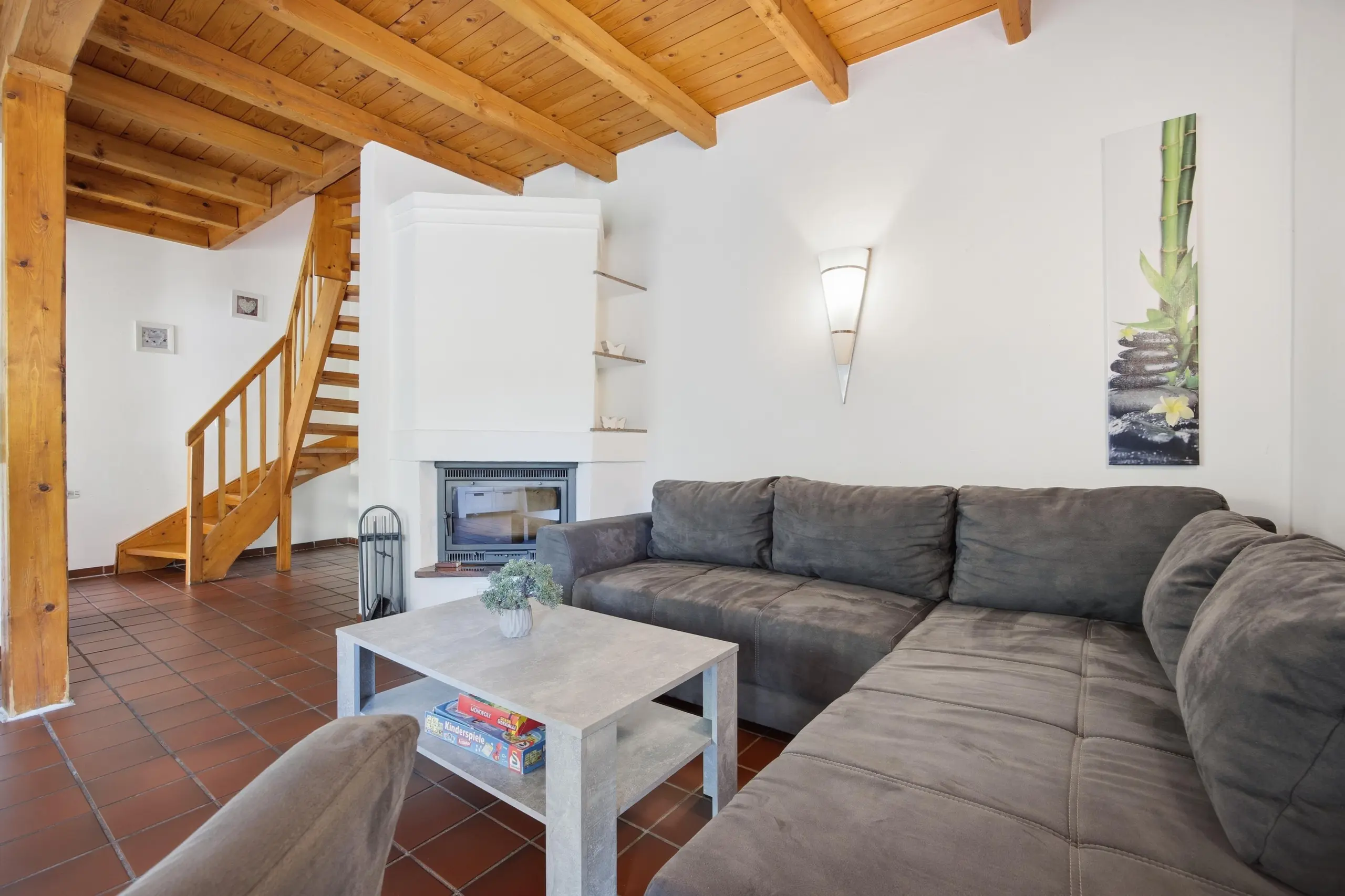 Cozy living room with a gray sectional sofa, concrete coffee table, and exposed wooden beam ceiling.