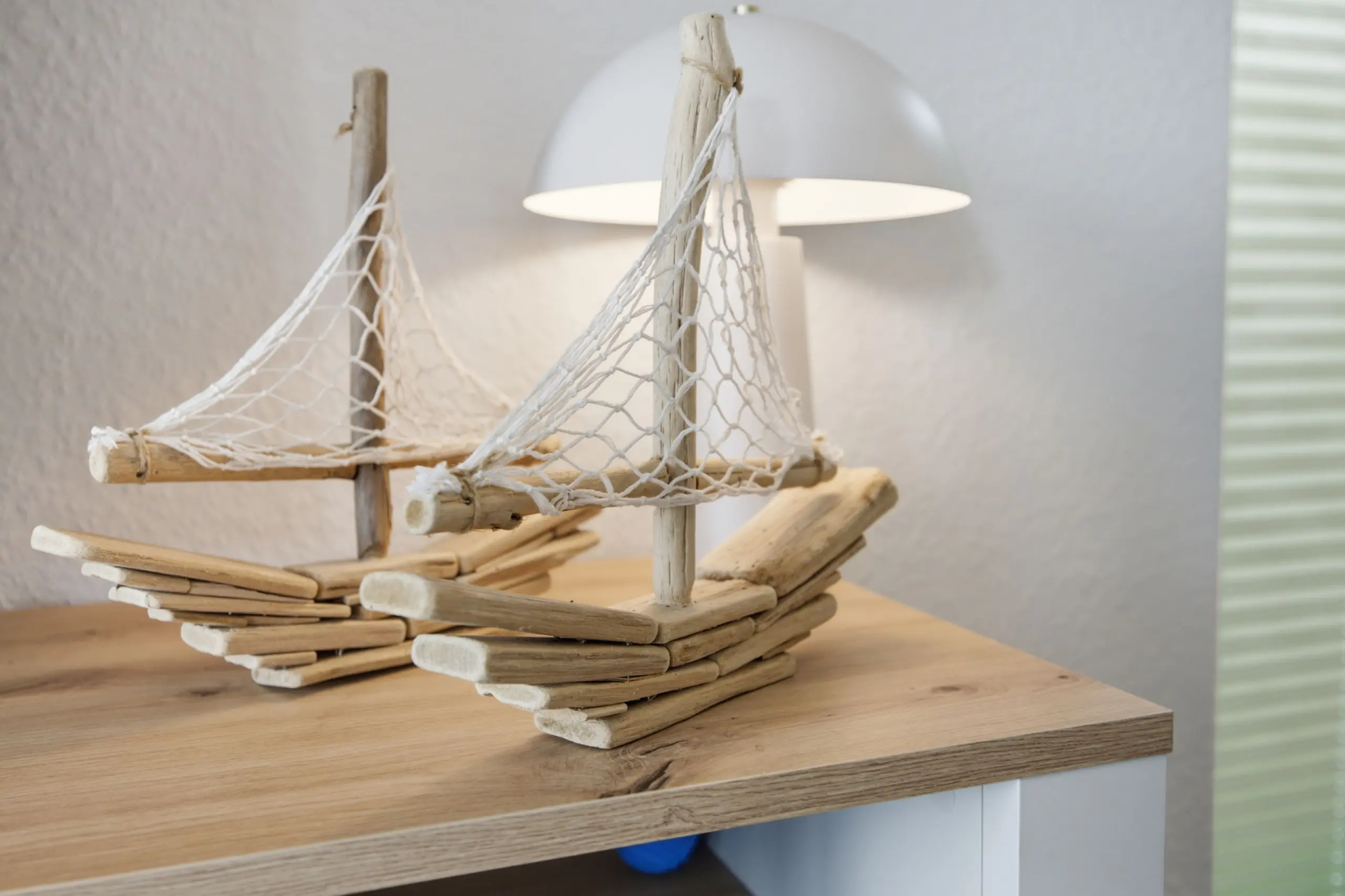 Decorative driftwood boat sculpture with white netting on a wooden tabletop indoors